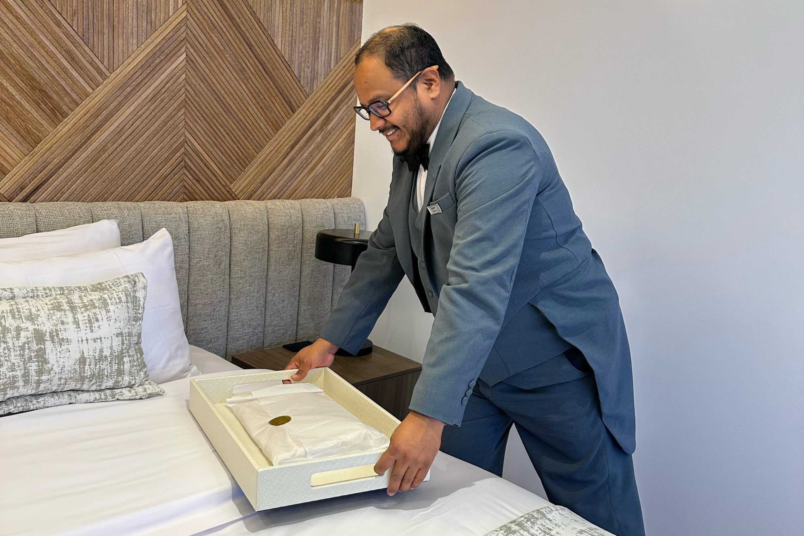 A butler aboard the luxury mega catamaran Hermes delivers freshly laundered clothing to a guest’s suite, as part of the personalized laundry service offered on board.