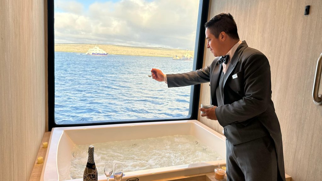 A butler aboard the luxury mega catamaran Hermes prepares the jacuzzi with the guest’s chosen bath salts, ensuring everything is ready for a relaxing soak after their hiking excursion