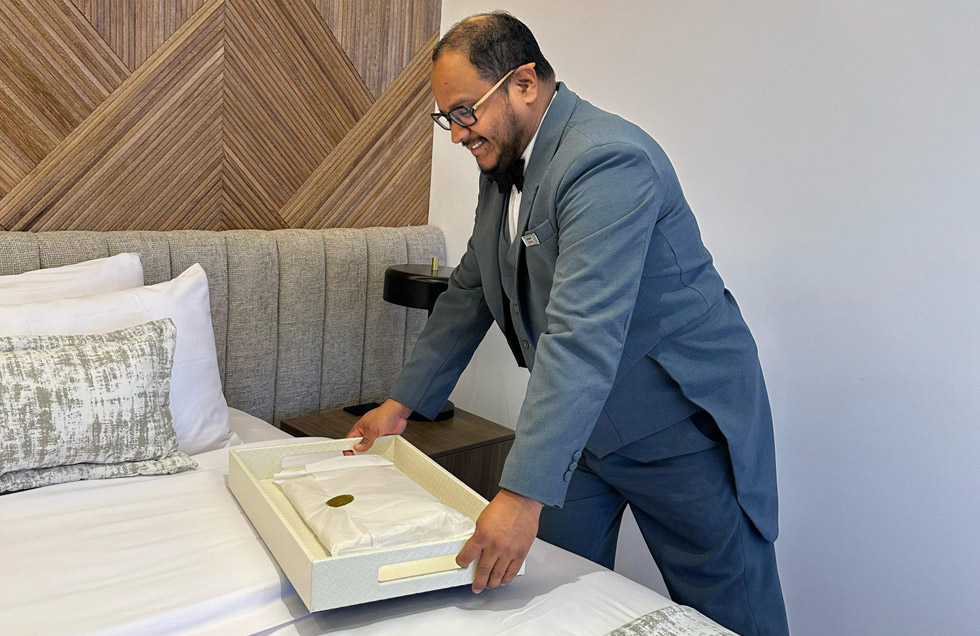 A butler aboard the luxury mega catamaran Hermes delivers freshly laundered clothing to a guest’s suite, as part of the personalized laundry service offered on board.