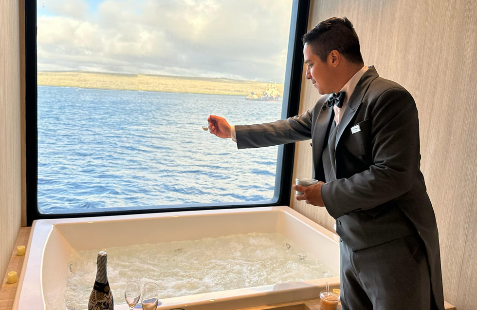 A butler aboard the luxury mega catamaran Hermes prepares the jacuzzi with the guest’s chosen bath salts, ensuring everything is ready for a relaxing soak after their hiking excursion