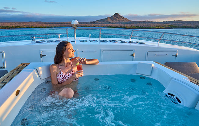 A guest relaxing in the jacuzzi on the sundeck of the best Galapagos cruise.
