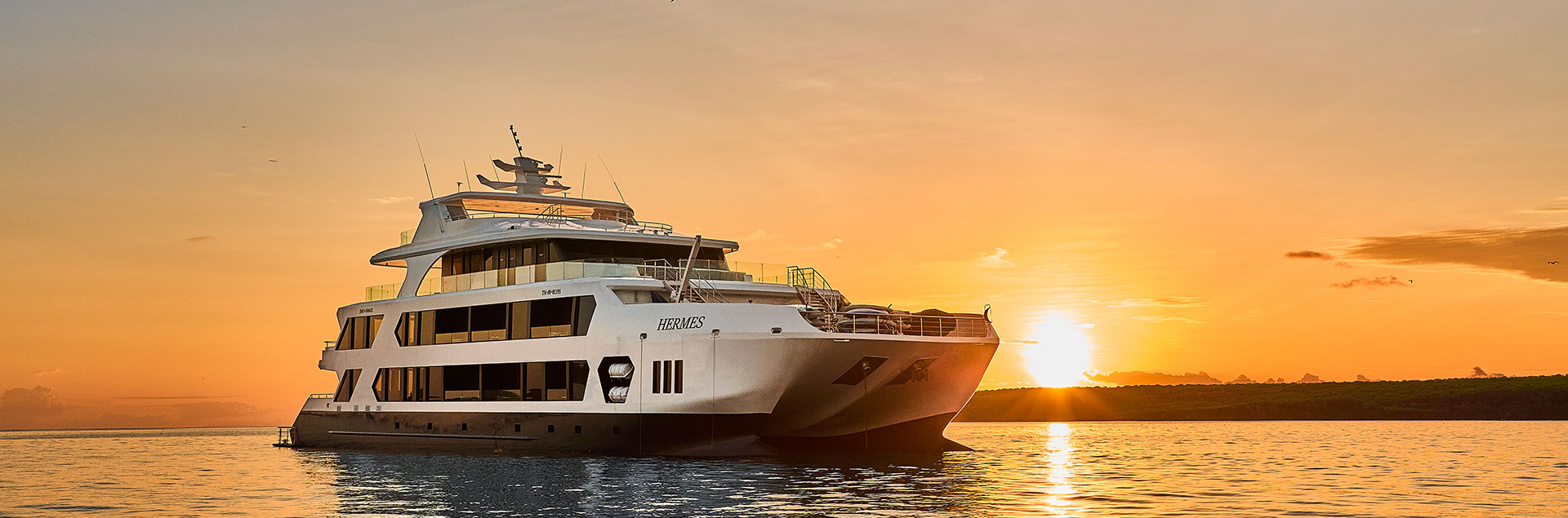 The Hermes Mega Catamaran sailing through the Pacific at sunset, the pinnacle of the ultra-luxury cruise experience in Galapagos.