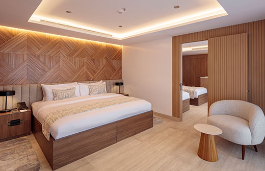 Modern interconnecting suite with oak accents and minimalist design, ideal for families on an ultra-luxury cruise.